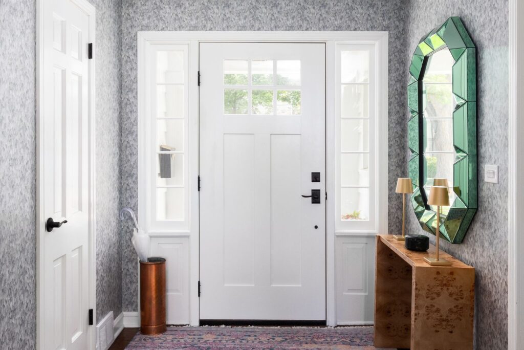white front door with entryway table and glass wall-hanging mirror