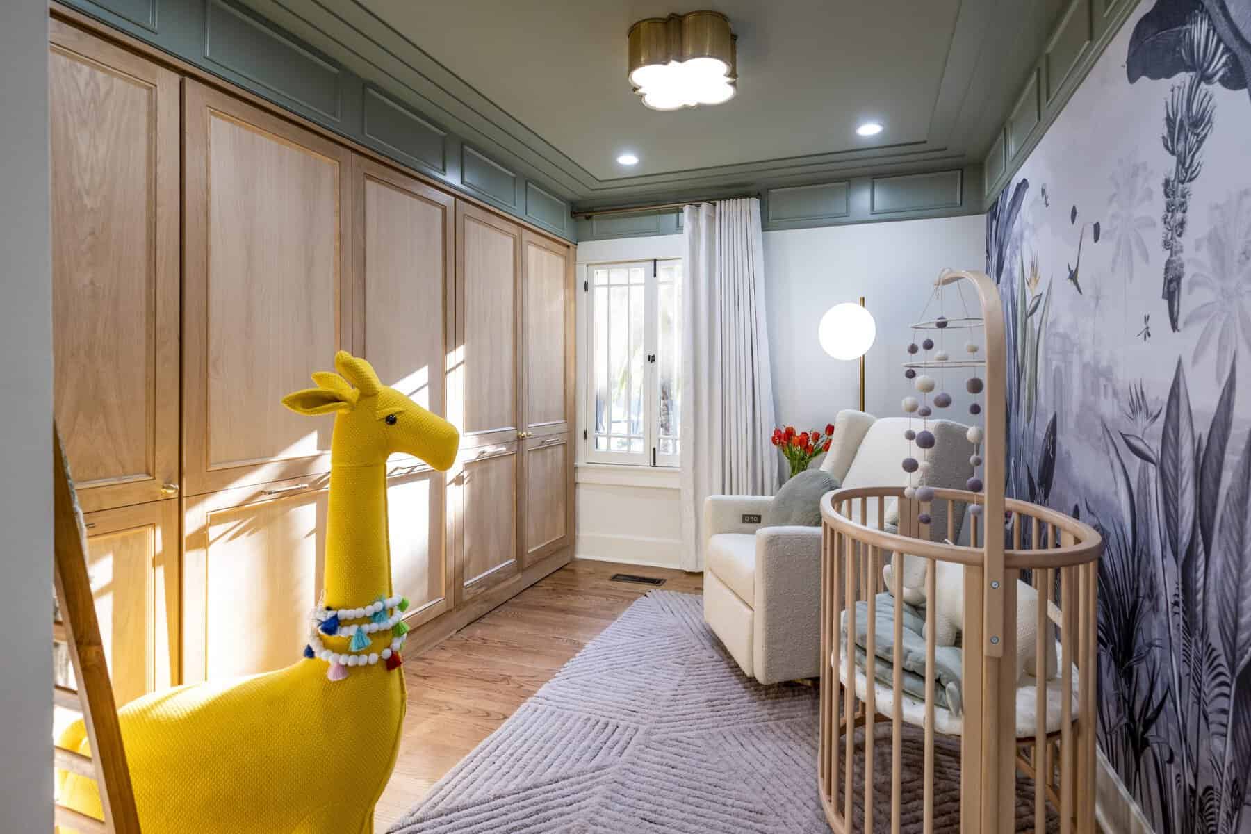 Nursery with wooden cabinets, yellow giraffe decor, and a crib beside a patterned wall