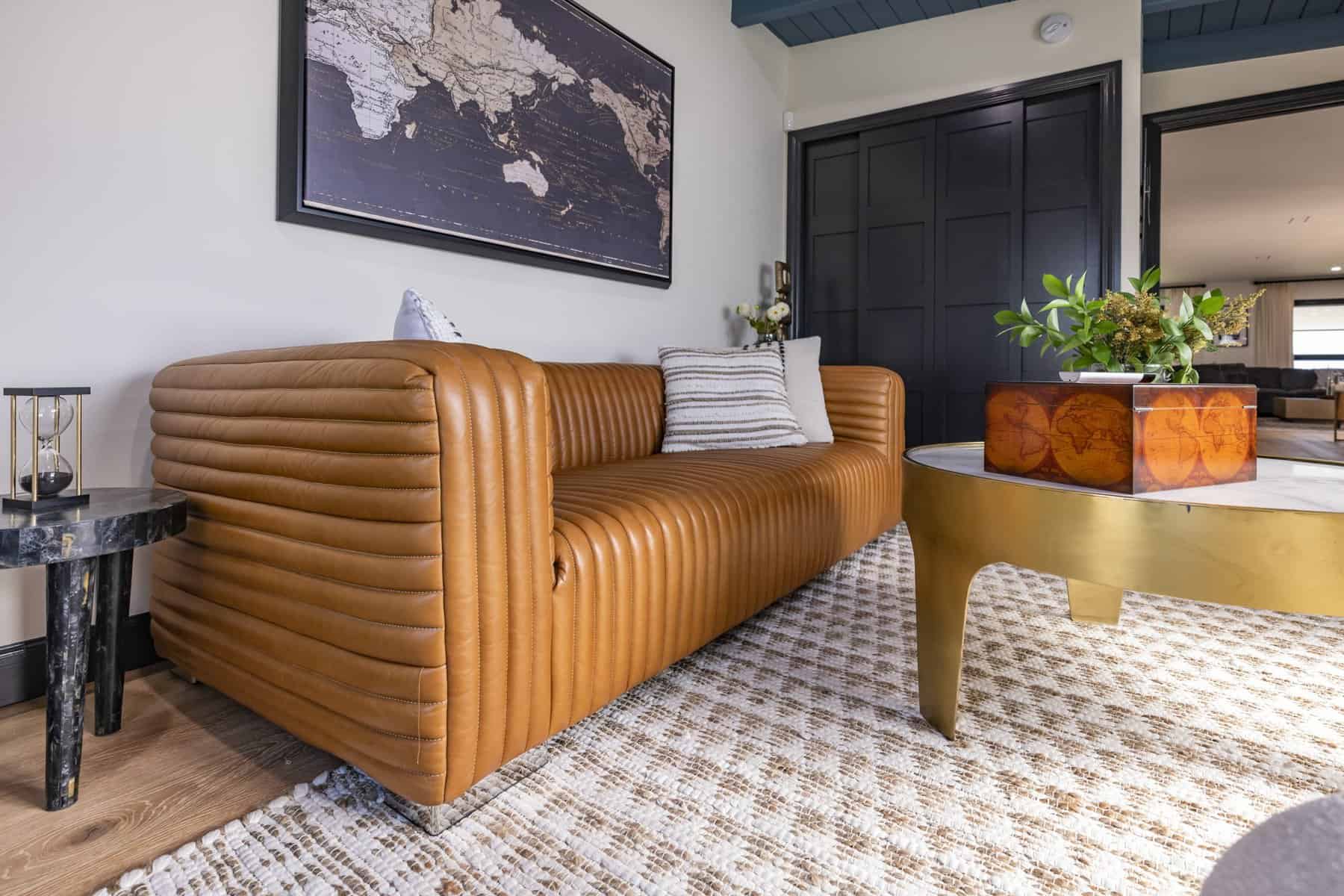 Tan leather sofa with pillows and round coffee table