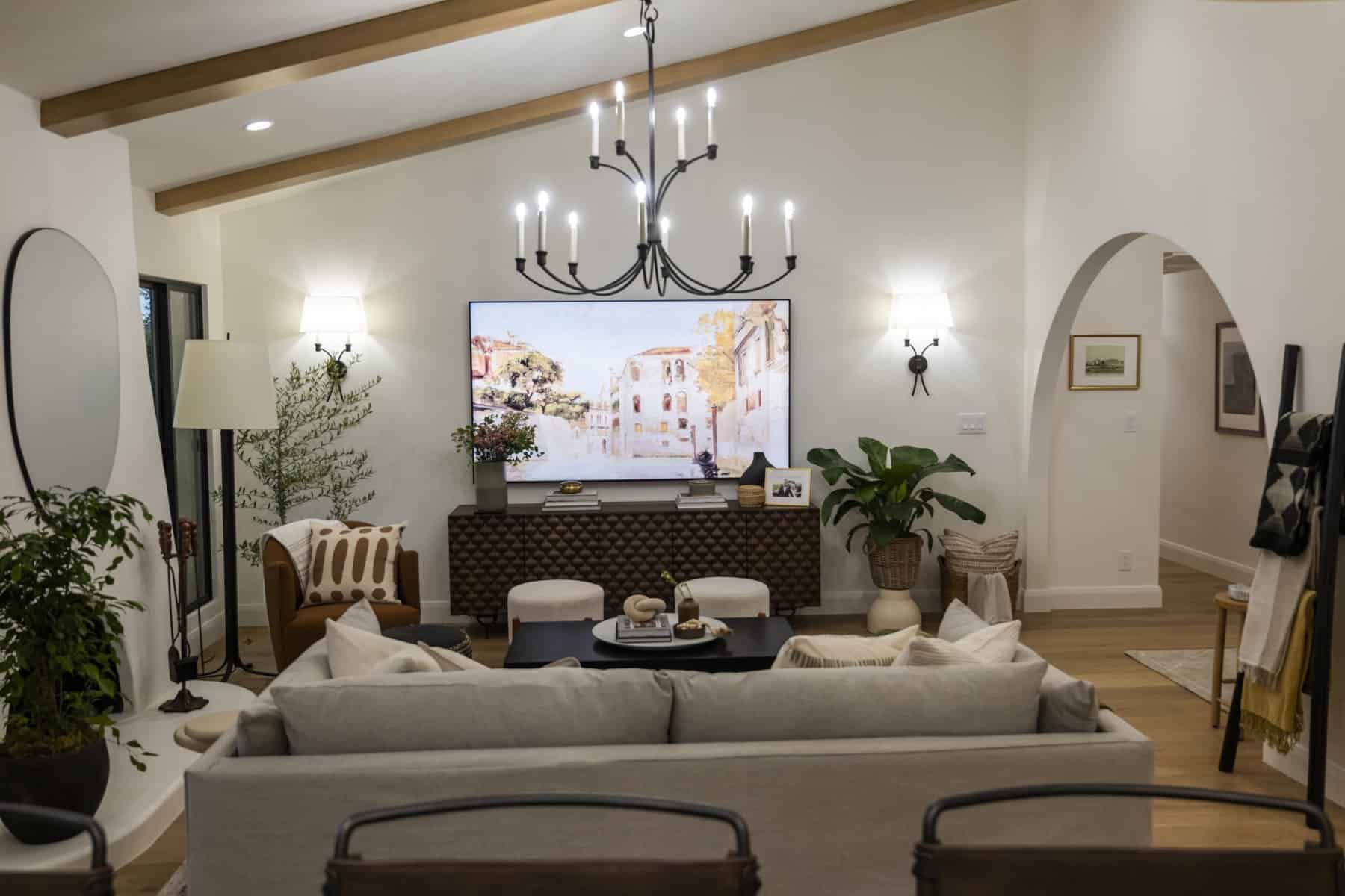 Open-concept kitchen and living area with gold pendant lights, gray sofa, and wood beam ceiling