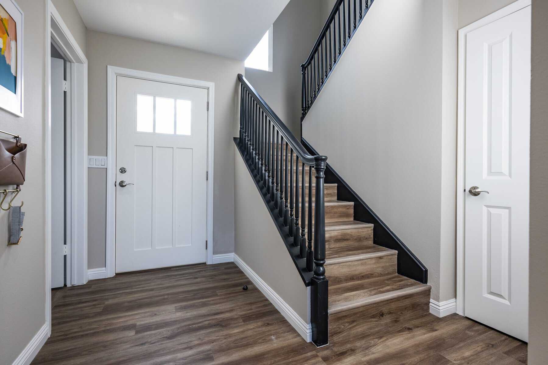 Entryway with wood flooring, white doors, and a staircase with black railings