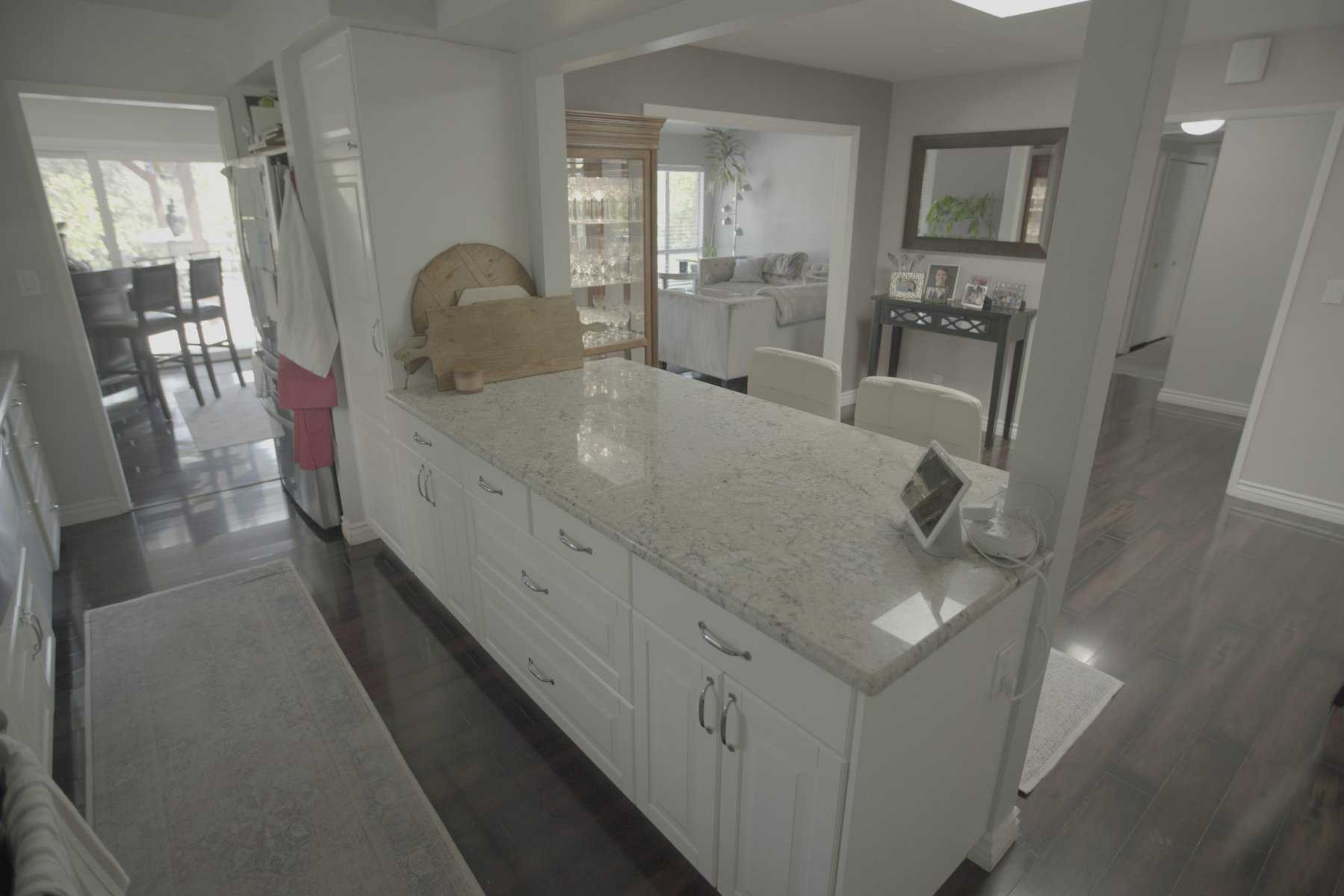 Bright kitchen with a granite island, white cabinetry, and open layout leading to dining and living areas