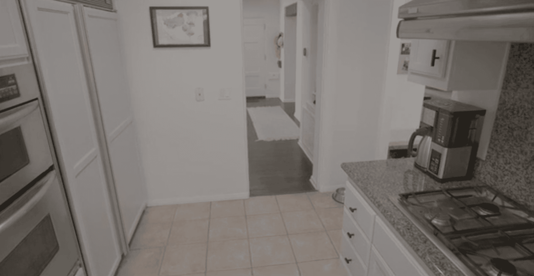 Bright kitchen with white cabinets, granite countertops, a gas stove, and a coffee maker