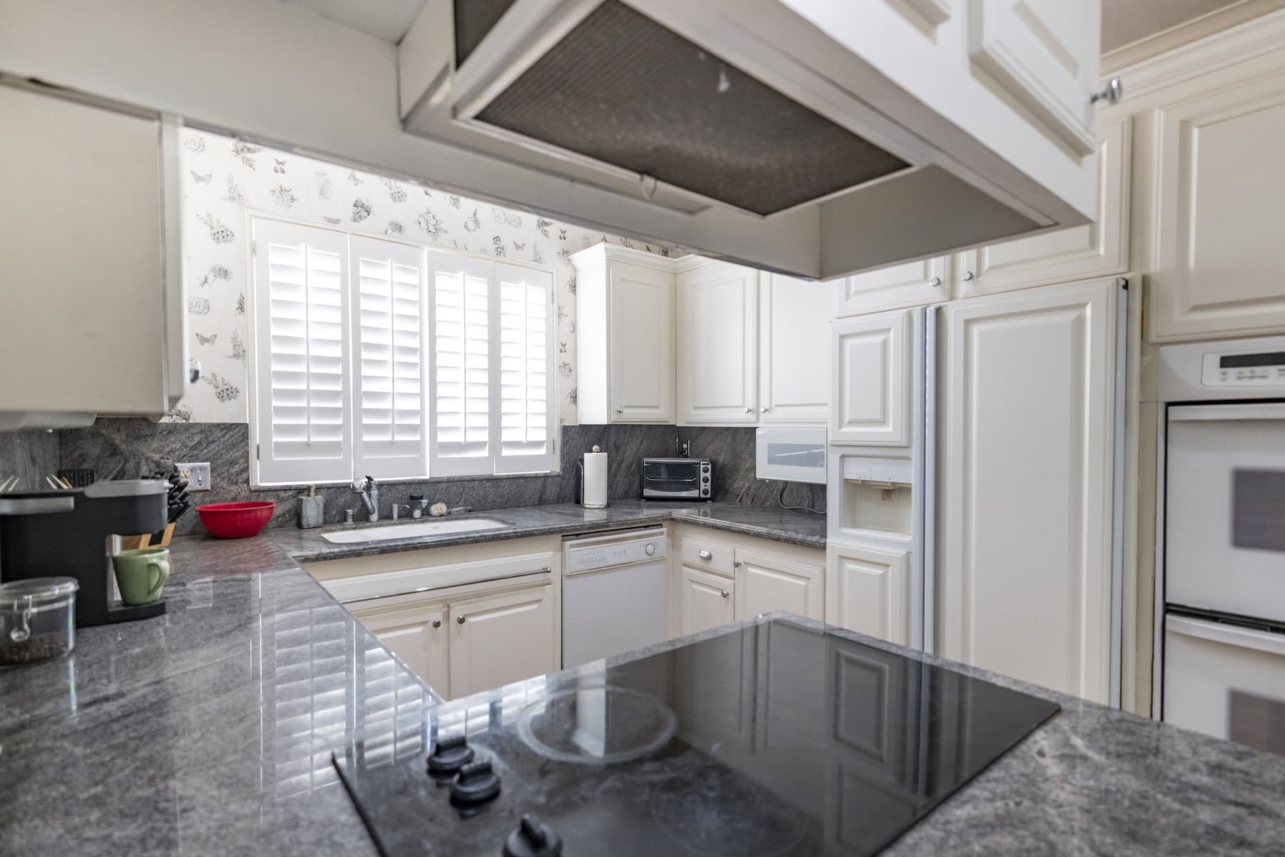 Traditional kitchen with white cabinets, gray granite countertops, and built-in appliances
