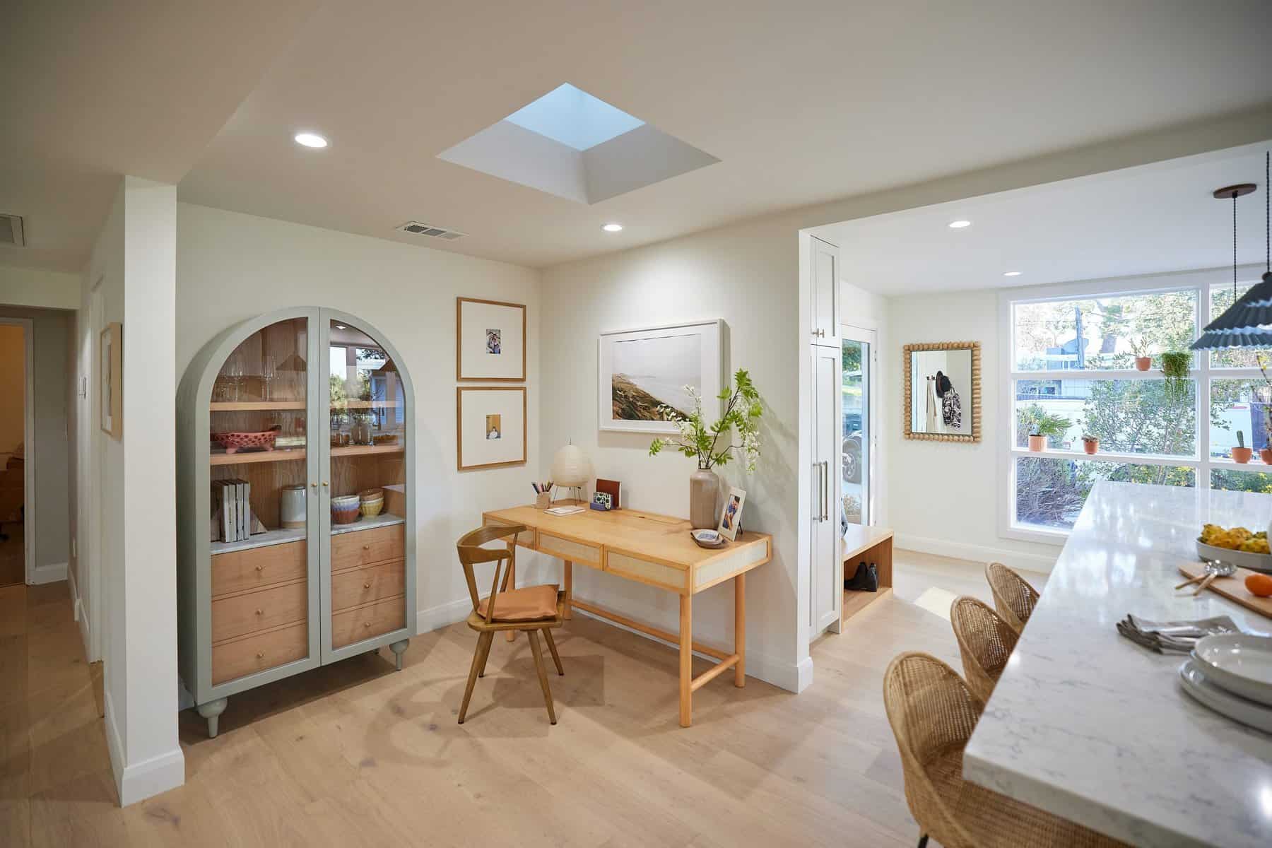 Bright open-concept home office and kitchen with natural wood furniture and skylight
