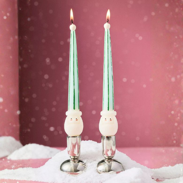 green and white tapered candles with santa at the base