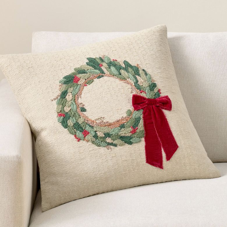 cream throw pillow with green wreath and red bow