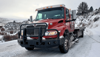 Towing truck from Frontier Repair & Towing on snowy road, ready for roadside assistance.