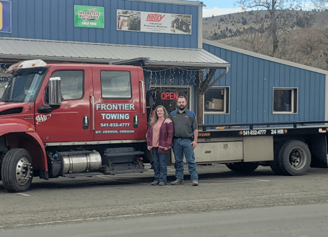 Frontier Towing truck with two staff members outside the shop.