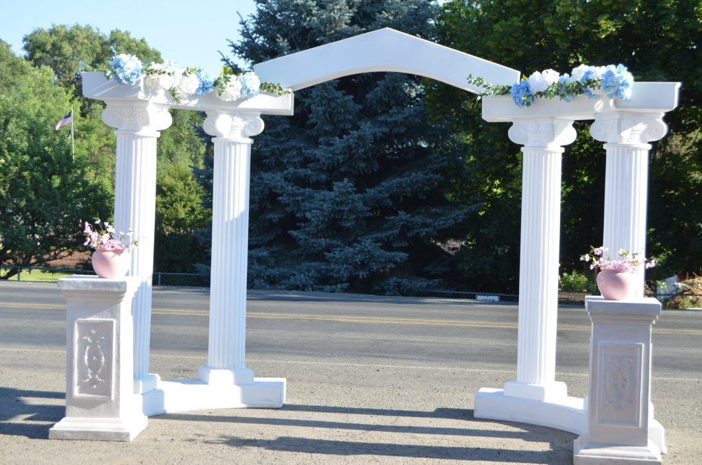Wedding arch for outdoor ceremonies, featuring white columns and floral accents, ideal for weddings.