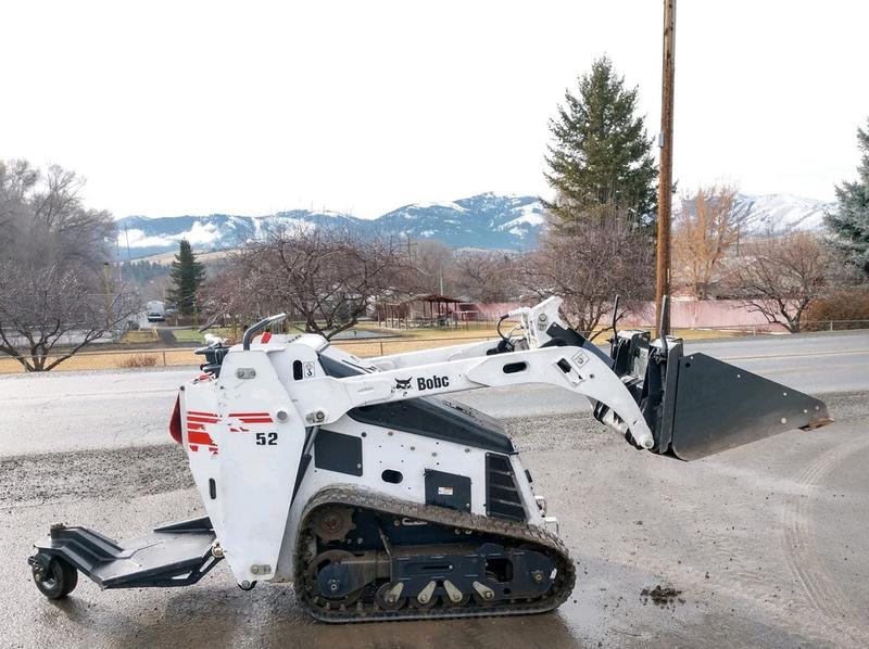 Mini skid steer loader with bucket attachment for construction and landscaping projects.