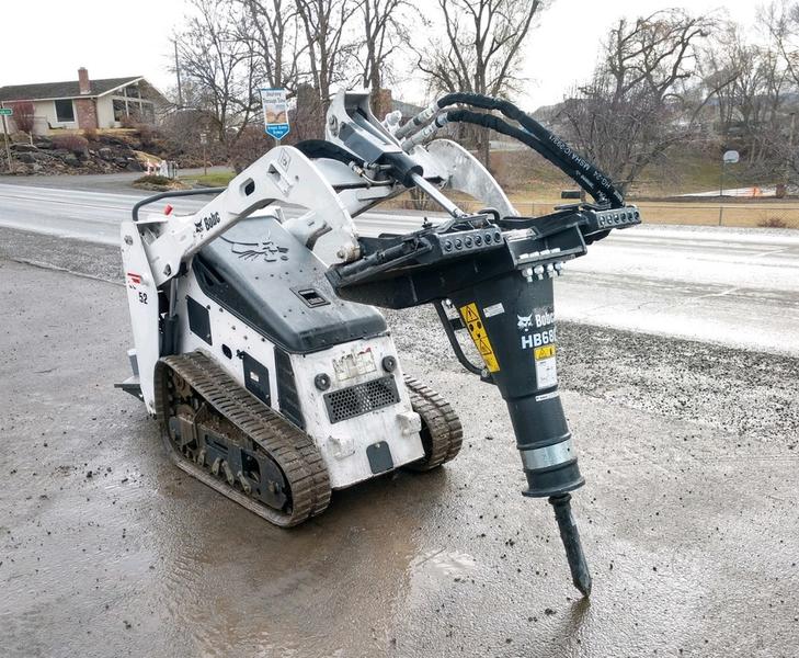 Mini skid steer with hydraulic breaker for construction and demolition projects.