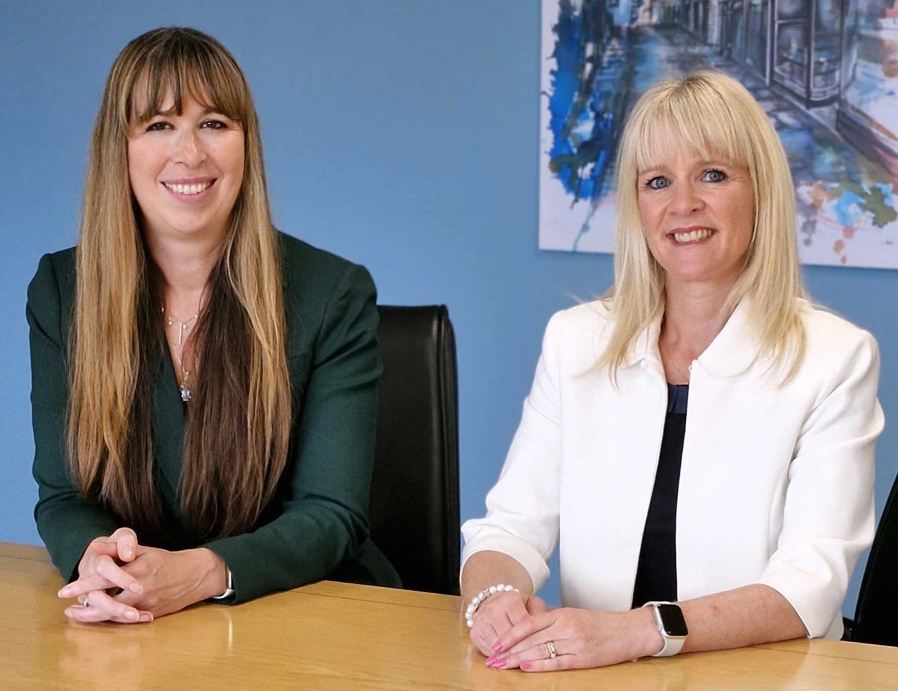 Professional women sitting at a conference table during a business meeting in an office setting.