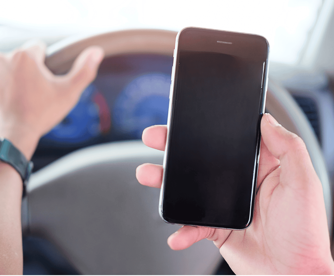 Smartphone held in hand while driving a car, close-up of mobile phone, digital technology, safe driving, road safety, automotive smartphone holder.