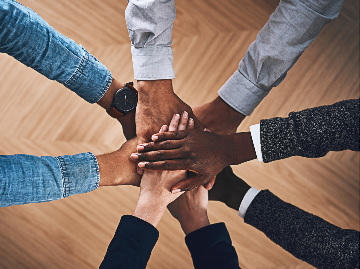 Diverse hands stacked together symbolising unity and collective effort.