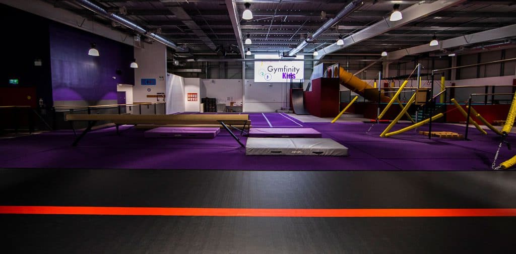 Gymfinity kids indoor trampoline park with gymnastics equipment and safety mats in a spacious, well-lit facility for children's activities and recreational fun.