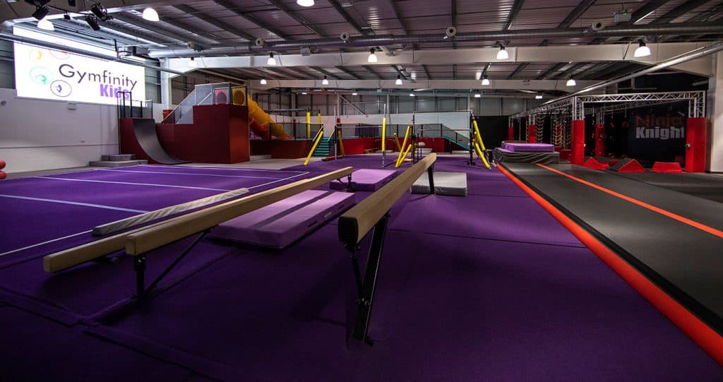 Bright indoor kids' trampoline and gymnastics park with various activity zones, colourful soft play equipment, and safety mats, creating a fun and secure environment for children to play and exercise.