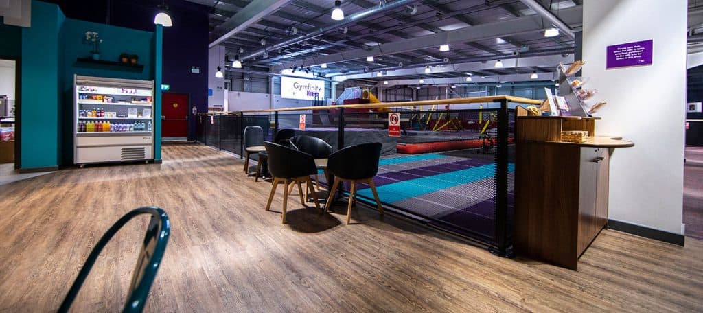 Indoor children's play area with soft padded flooring, seating area, and vending machine for snacks and drinks in a modern entertainment centre.