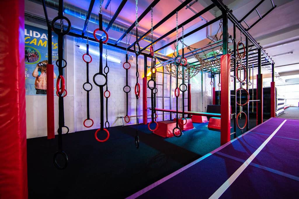 Climbing fitness equipment with ropes, rings, and obstacle elements in an indoor gym designed for agility and strength training. Suitable for children and adults seeking active play or fitness.