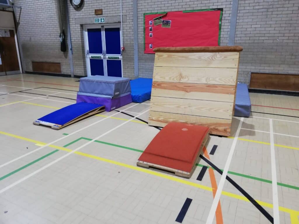Climbing equipment and mats set up inside a gymnasium for gymnastics training or practice.
