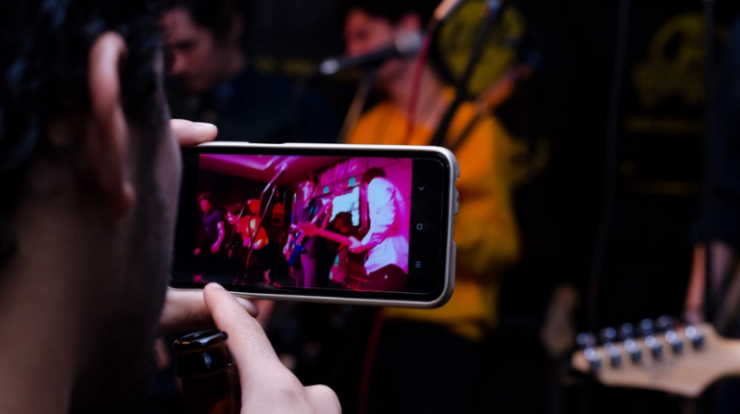 Concert photography of people recording live music performance on smartphone in a vibrant and energetic concert setting environmental scene.