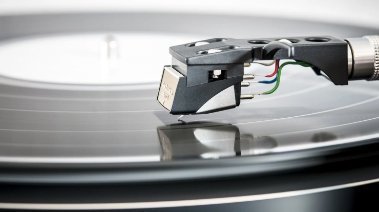 Turntable with tonearm and stylus playing vinyl record, high-quality audio equipment, music production, DJ equipment, analog music technology, close-up shot for music and audio enthusiasts, vintage-inspired audio gear.