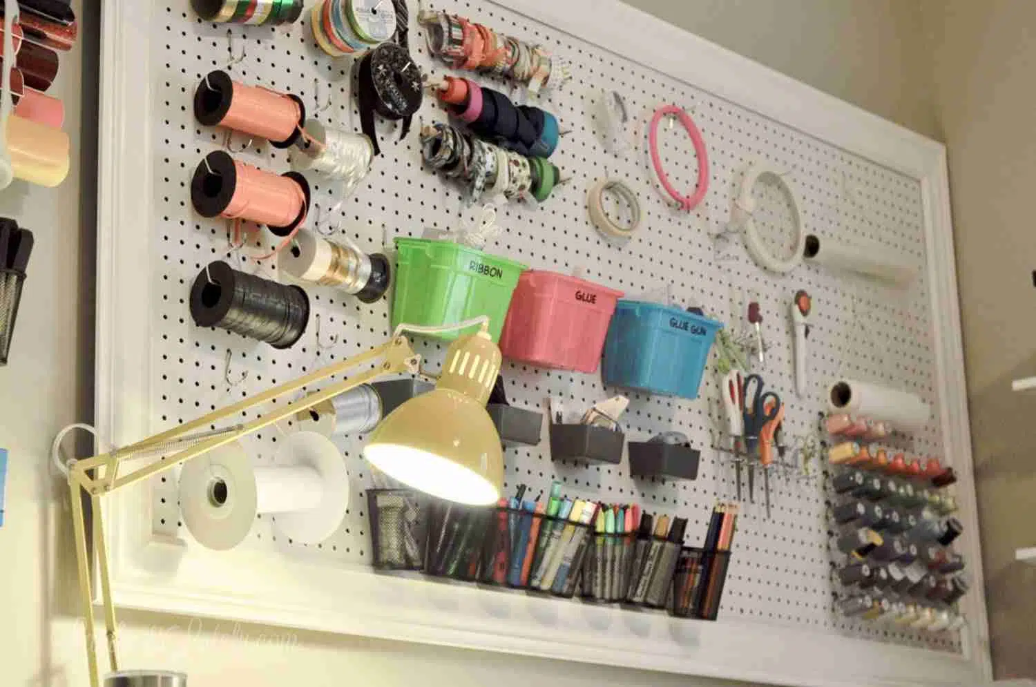 craft room peg board with yellow desk light.
