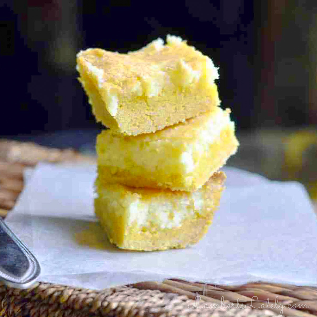 lemon chess bars stacked on a piece of parchment paper.