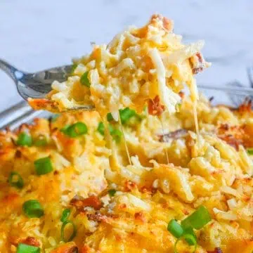 lifting a spoonful of crack potato casserole out of the baking dish.
