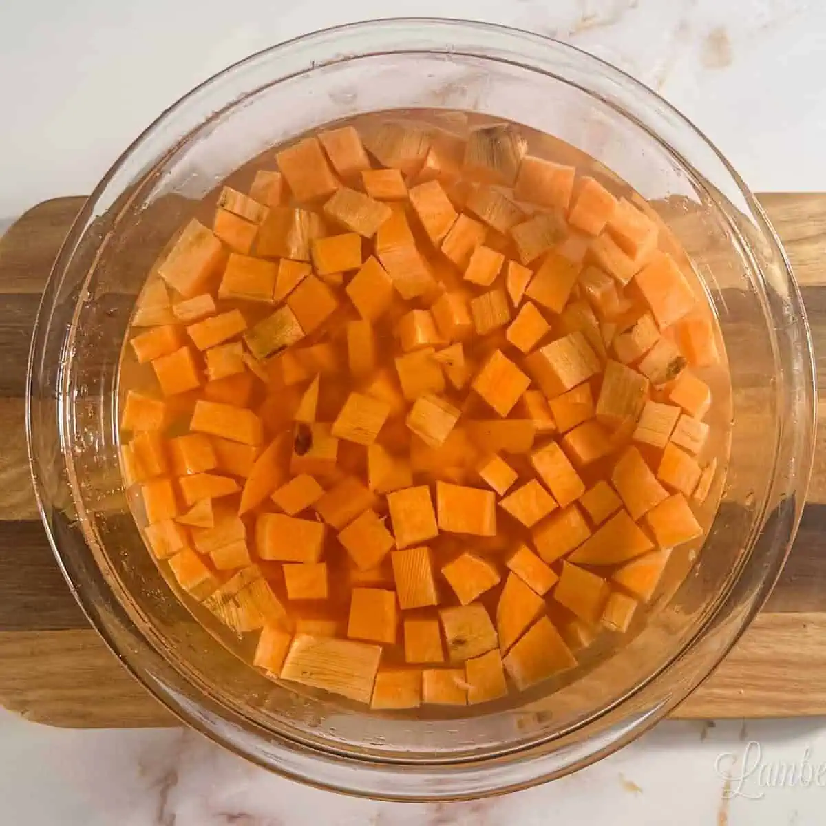 sweet potato cubes in a glass bowl of cold water.