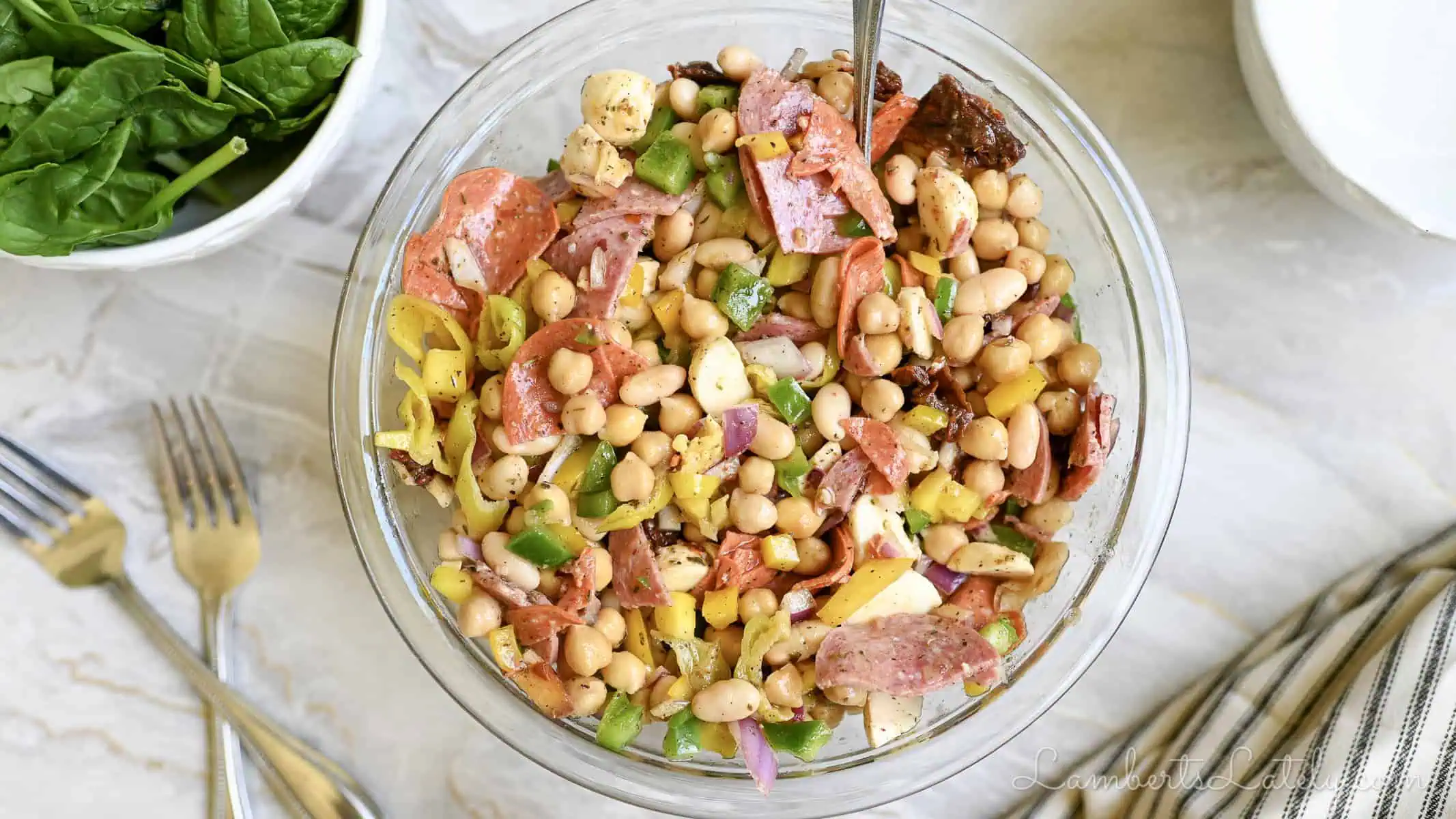 italian dense bean salad in a serving bow, surrounded by bowls, lemon, and napkin.