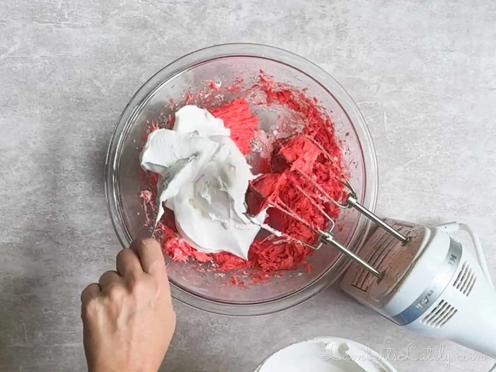 mixing cool whip into the bowl of mixed ingredients.