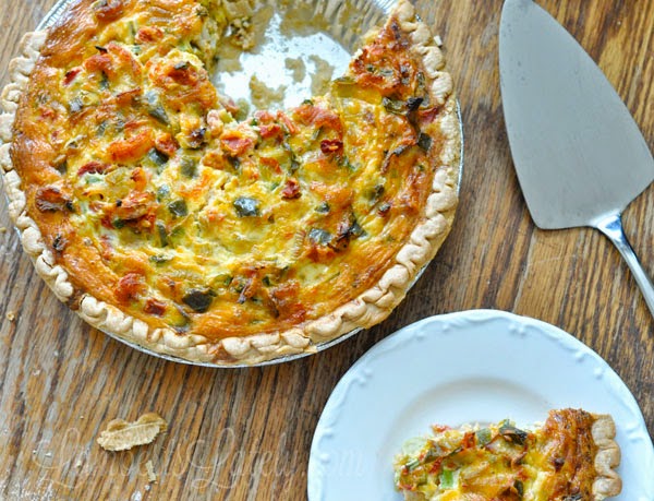slice of cajun crawfish quiche on a white plate, next to a pie and a serving utensil.