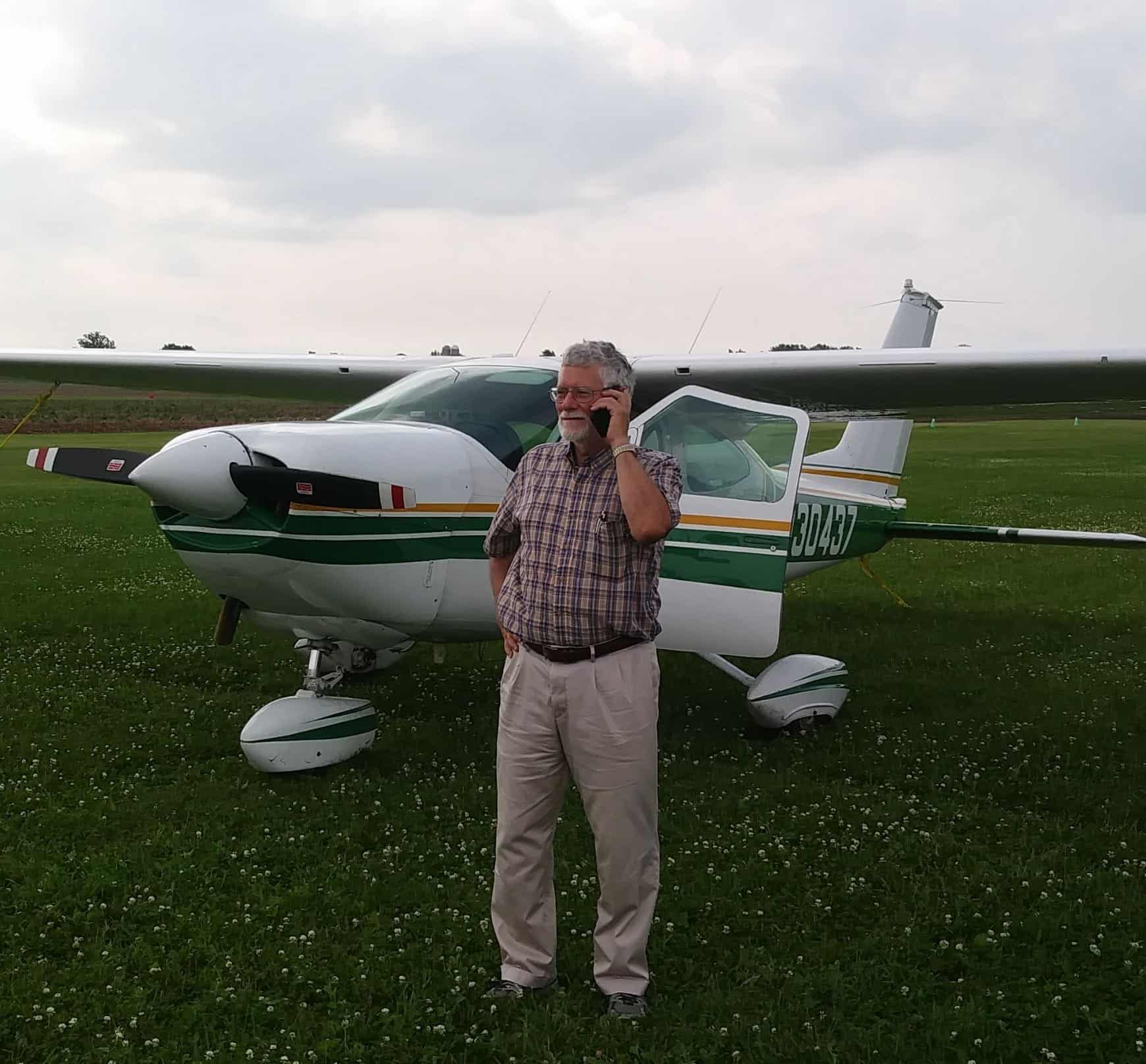 Man on cell phone standing next to plane