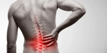 Man holding lower back showing pain area in red, demonstrating back discomfort.
