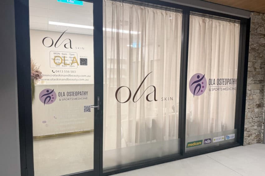 Osteopath clinic entrance with glass doors and signage for OLA Osteopathy & Sports Medicine.