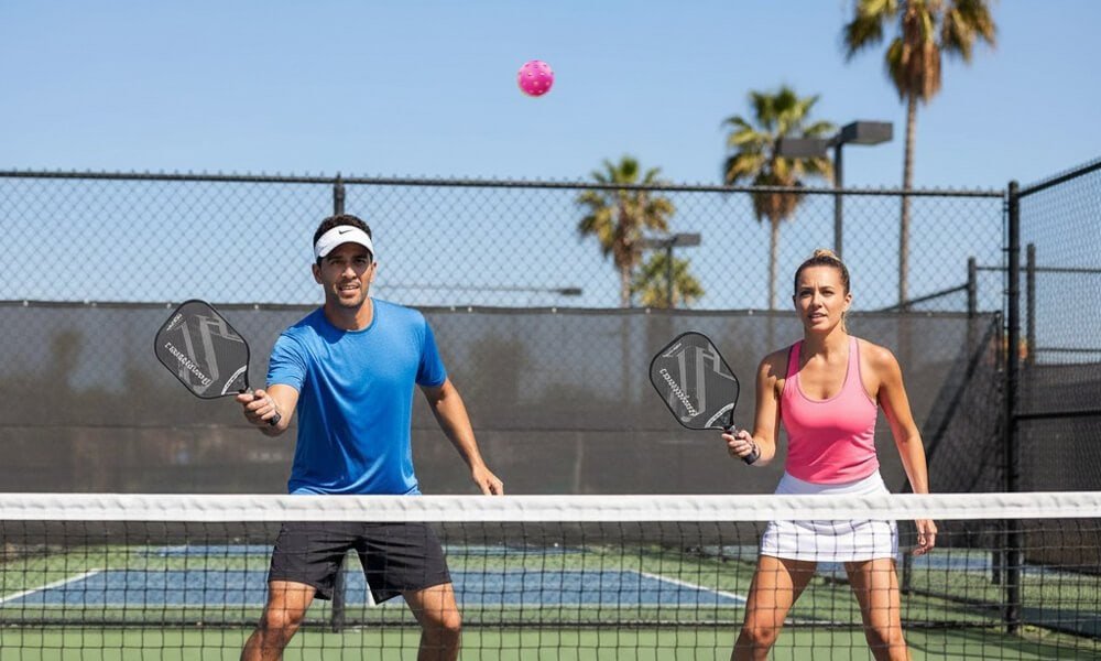 man and woman playing pickleball with carbon fiber paddles on a court