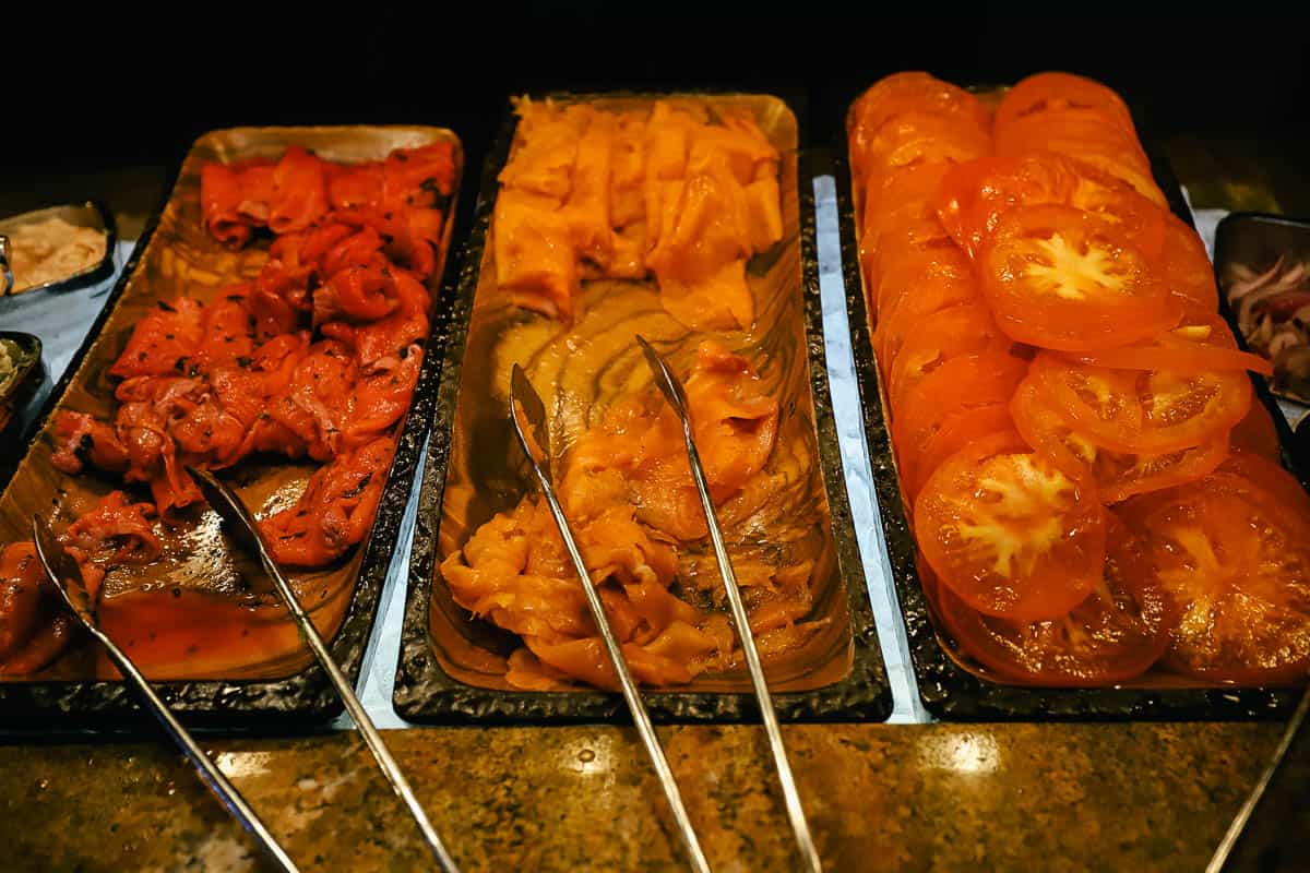 two types of smoked salmon and a tray with sliced tomatoes 