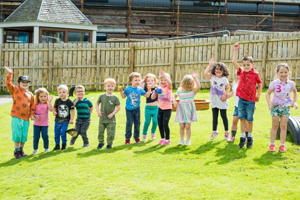 Vibrant children playing outdoors in a safe, welcoming childcare environment at Thrive Childcare in the UK.