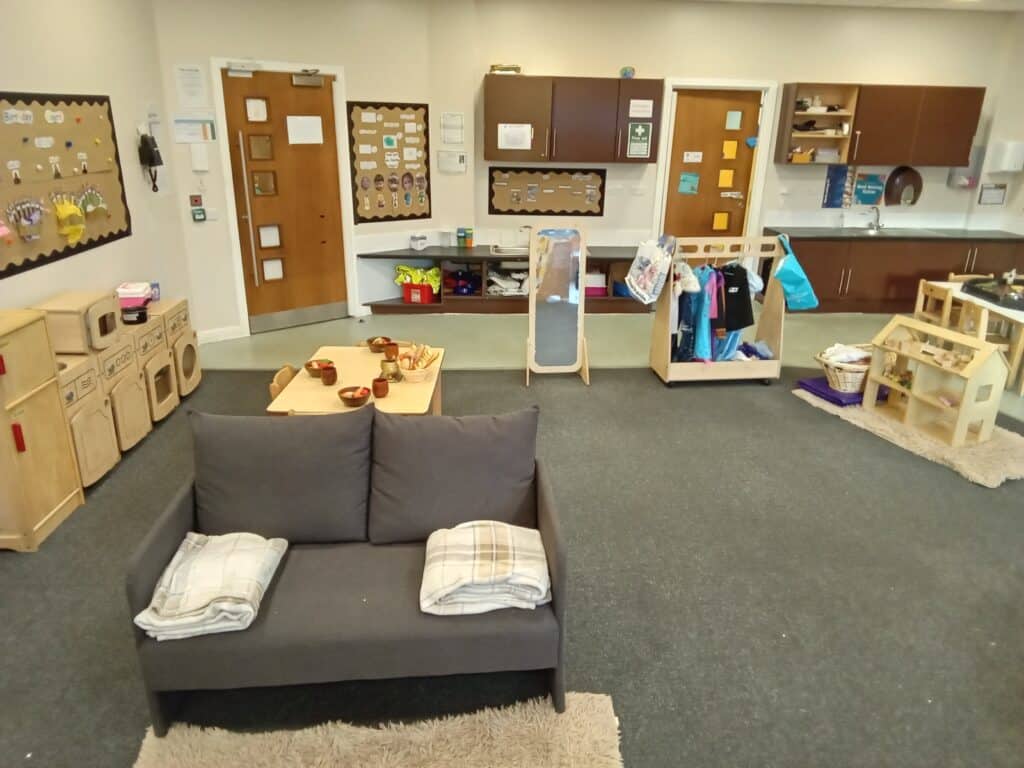 Bright indoor childcare playroom with toy kitchen, reading corner, and activity zones, perfect for early childhood development at Thrive Childcare.