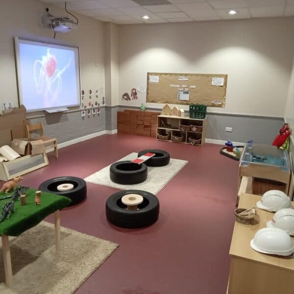Colourful indoor toddler play area with toys, soft tyres, and educational displays at Thrive Childcare, highlighting a safe, engaging environment for early childhood development and learning.