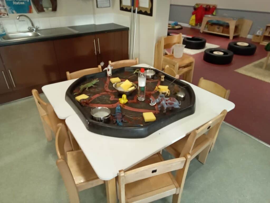 Pretend play sensory table with toy animals, rubber ducks, and foam blocks in a toddler-friendly classroom at Thrive Childcare, promoting imaginative learning and fine motor skills.
