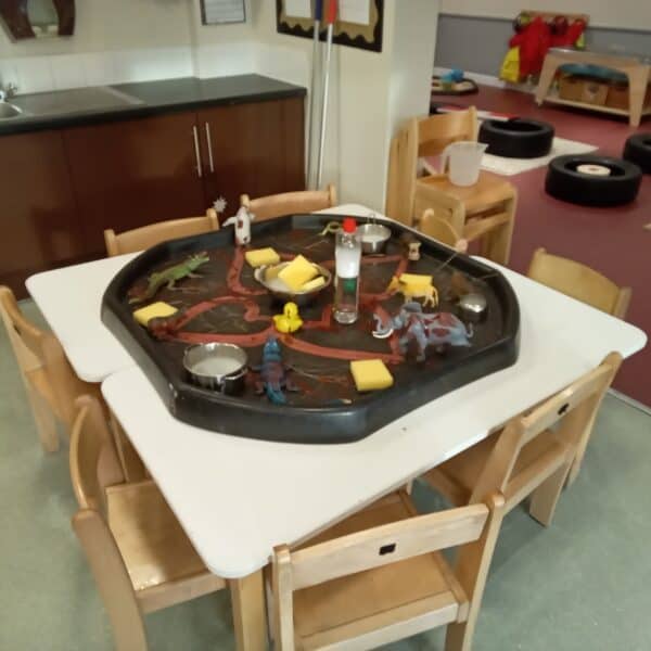 Pretend play sensory table with toy animals, rubber ducks, and foam blocks in a toddler-friendly classroom at Thrive Childcare, promoting imaginative learning and fine motor skills.