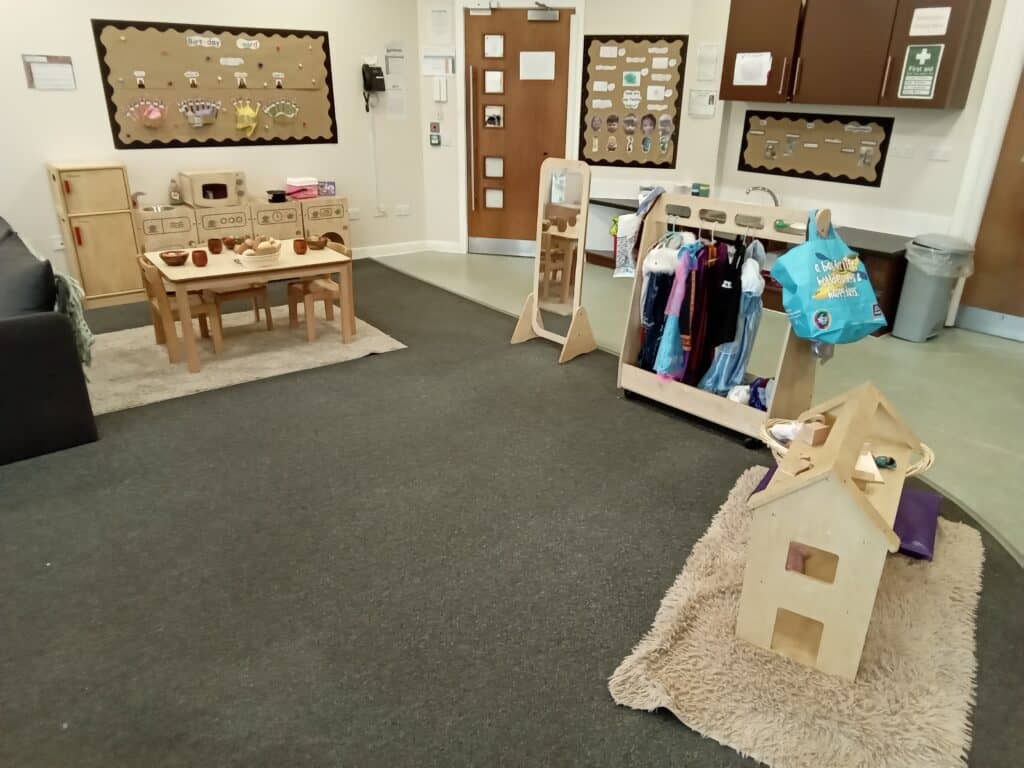 Bright indoor play area at Thrive Childcare with wooden toys, child-sized furniture, coat rack, and educational displays, providing a safe and engaging environment for young children.
