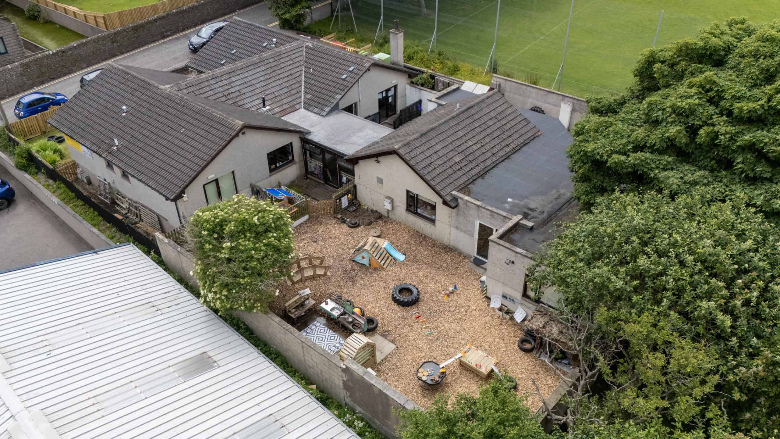 Bright and safe outdoor play area at Thrive Childcare featuring playground equipment, tires, sandpit, and activity stations within a secure enclosed yard.