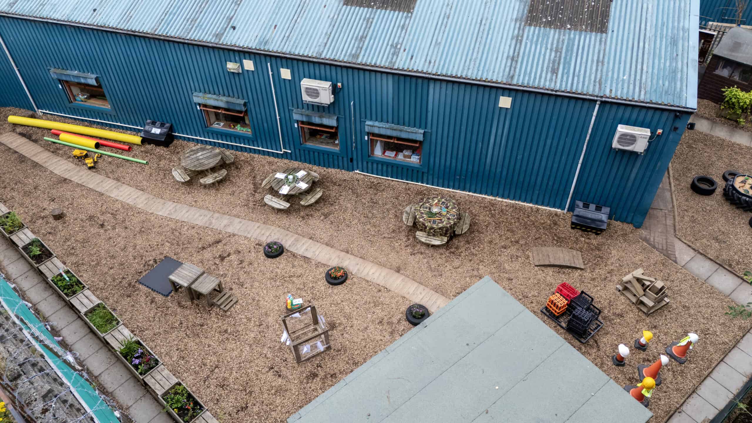 Bright blue childcare centre building with outdoor play area, gardening beds, and children’s equipment, providing a safe, engaging environment for early childhood development and learning.