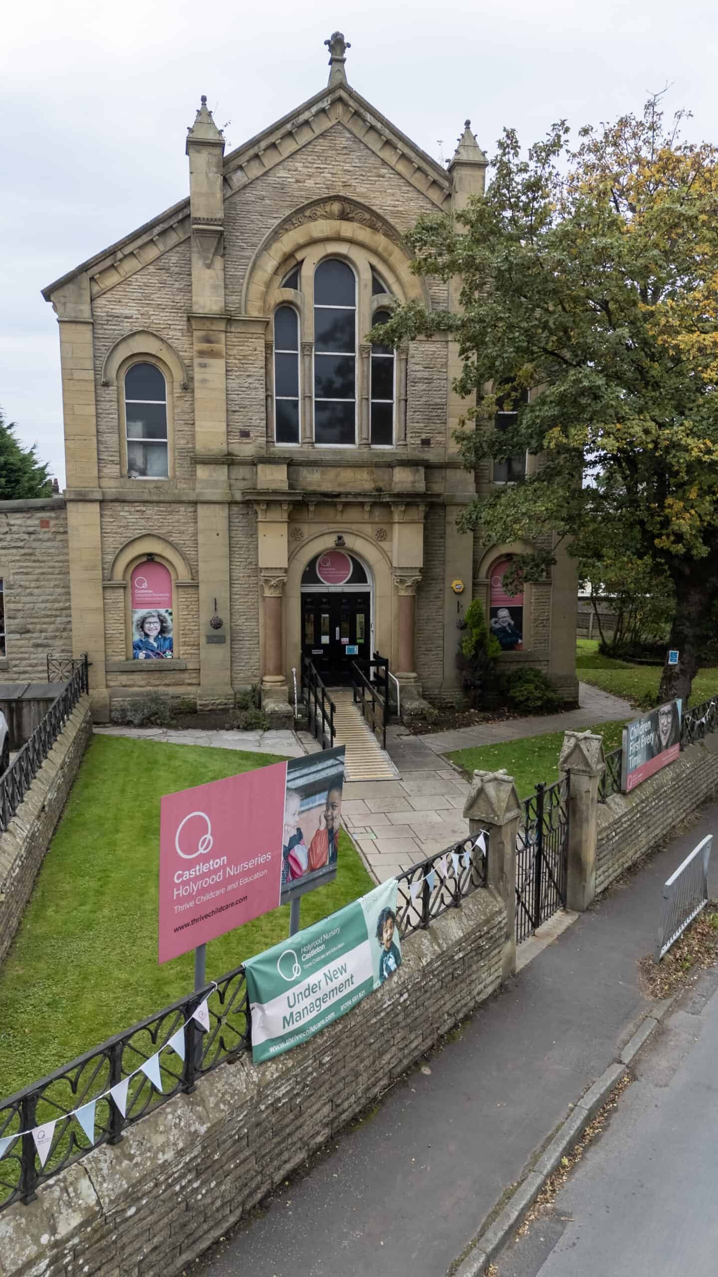 Brighton-based Thrive Childcare nursery building with historic architecture, promotional banners for childcare services, and autumn trees, showcasing a trusted environment for early childhood education and development.