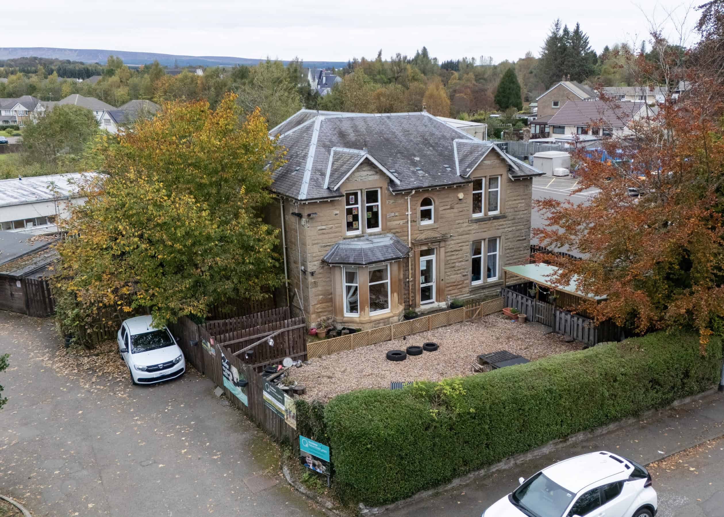 Aerial view of Thrive Childcare's welcoming building surrounded by trees with autumn foliage, providing a safe, nurturing environment for children in a friendly community setting.