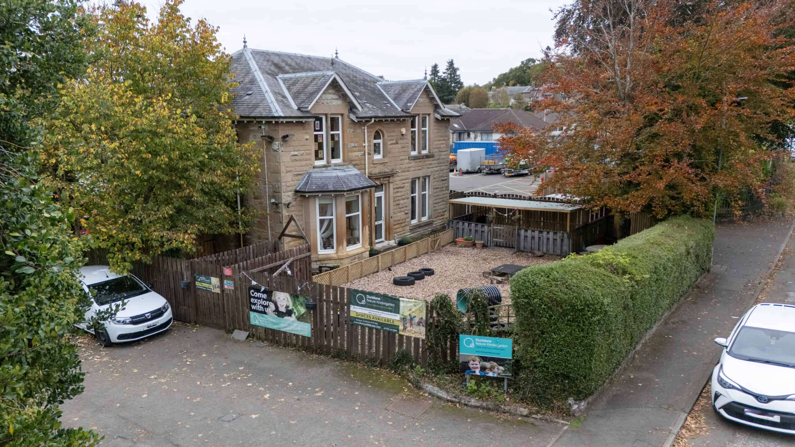 Bright outdoor view of Thrive Childcare with a secure playground, surrounded by trees and fencing, providing a nurturing environment for early childhood education and development in a safe, family-friendly setting.
