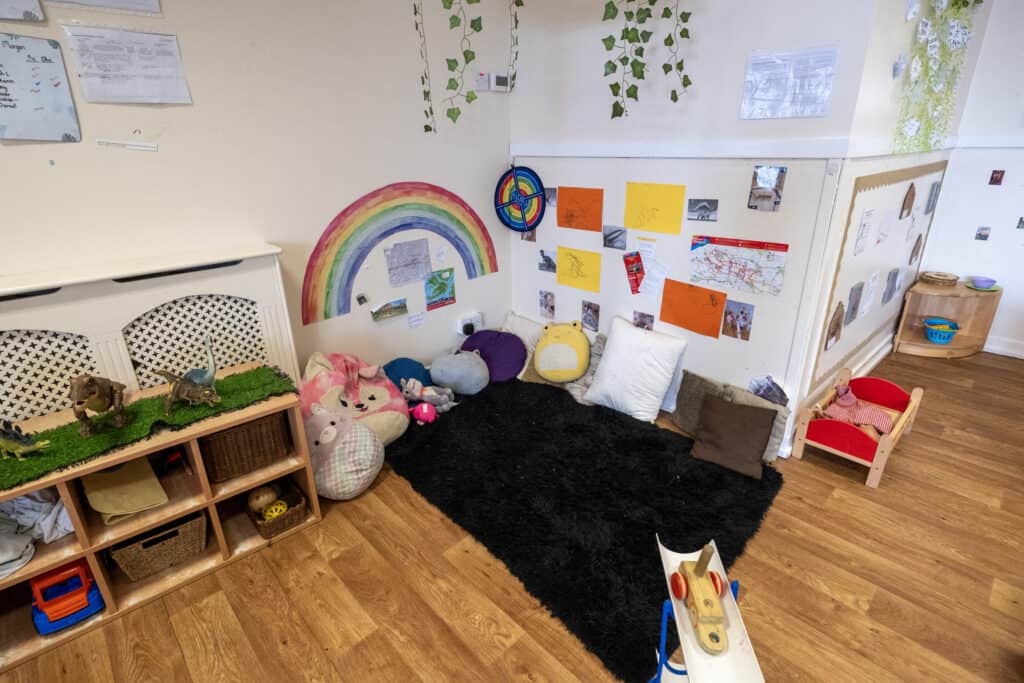 Bright and colourful nursery corner at Thrive Childcare, featuring toys, cushions, and educational decorations, creating a welcoming environment for early childhood play and learning.